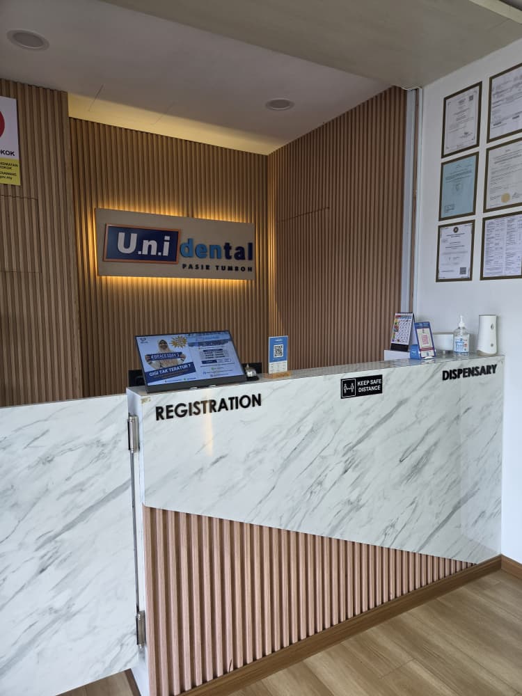 Kaunter pendaftaran u.n.i Dental Pasir Tumboh dengan logo bercahaya